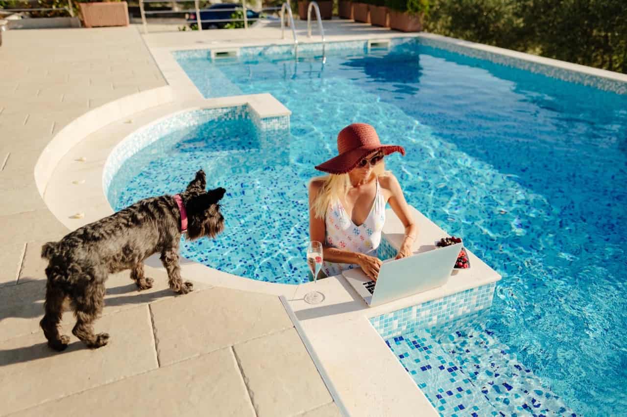Woman working on laptop in pool with dog — Good Life Pools